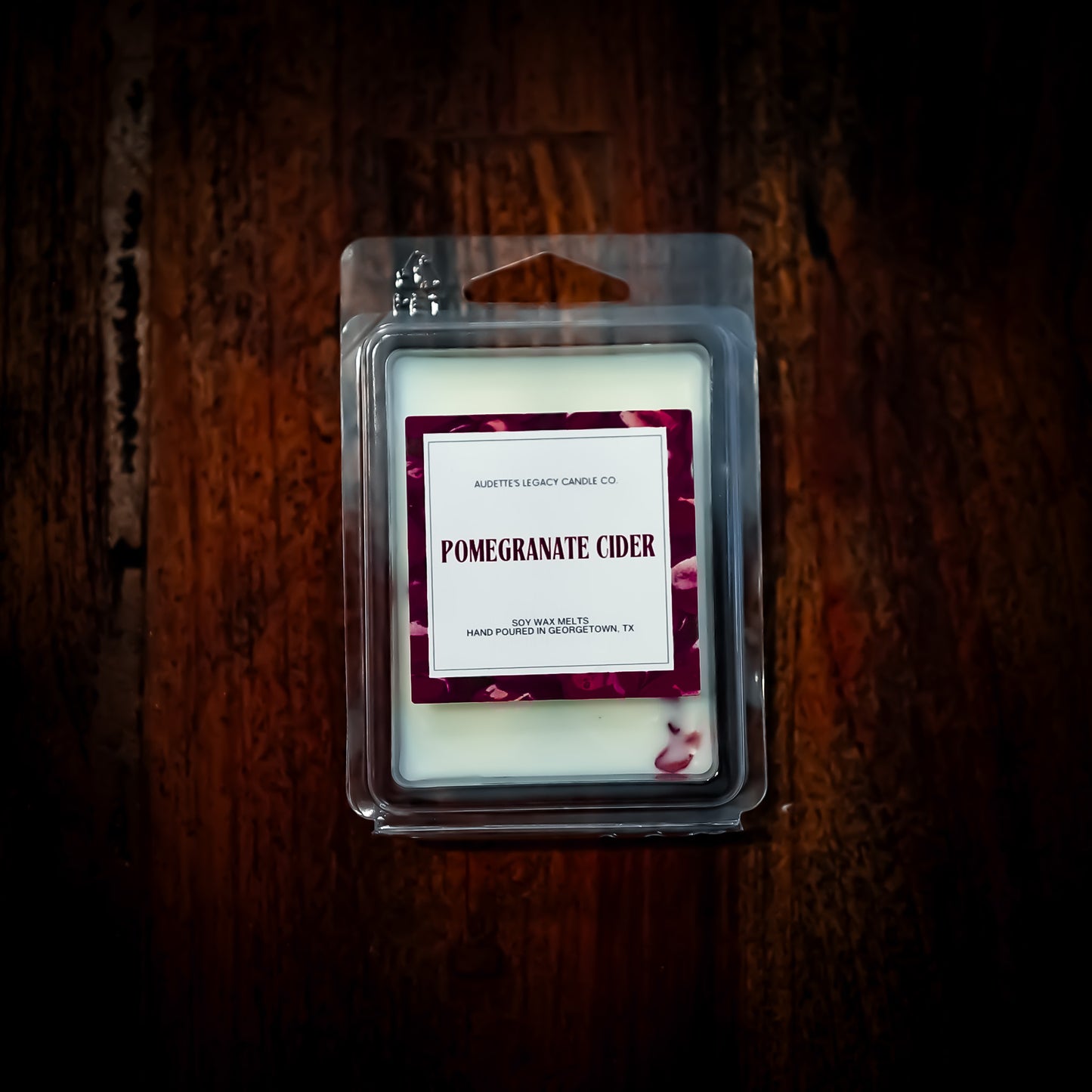 Wax melt in packaging labeled 'Pomegranate Cider' on a wooden surface